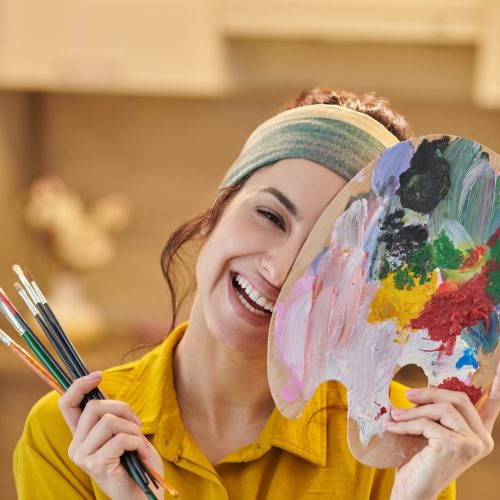 Artistry. A pretty young woman with a palette and brushes in hands